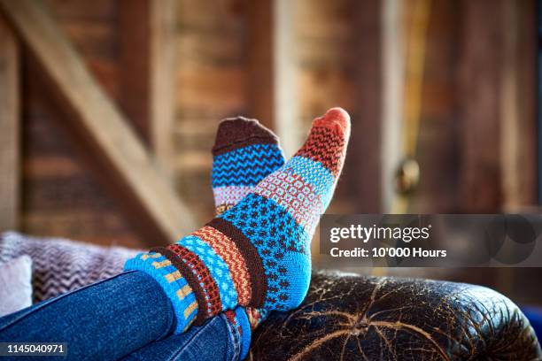 person wearing patterned socks with feet up on leather sofa - wolle stock-fotos und bilder