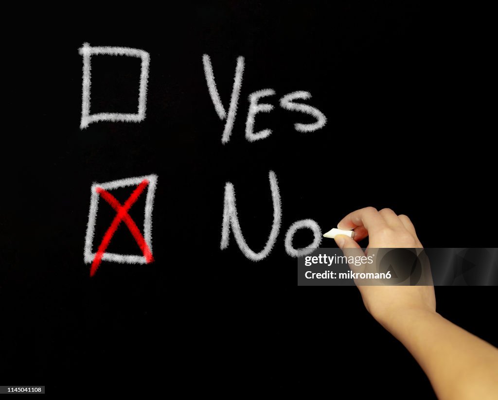 Hand drawing a tick the box question are with chalk in black board