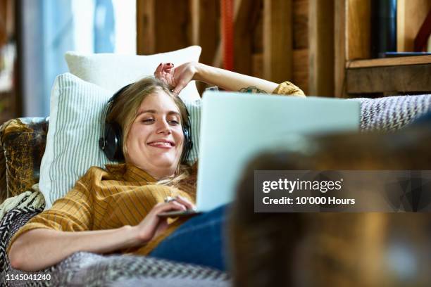 cheerful mid adult woman using laptop and smiling with headphones - easy stockfoto's en -beelden