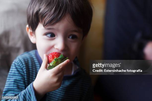 photograph of a child's expression eating a strawberry - child eating a fruit stockfoto's en -beelden