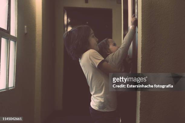 photograph of an elementary school boy helping his little sister - solo bambini foto e immagini stock