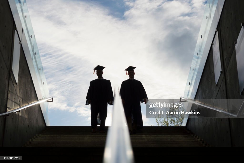 Silhouet van twee College afgestudeerden klimmen stappen