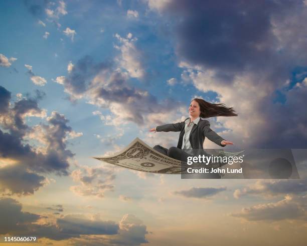 businesswoman riding a fly carpet dollar bill - 空飛ぶ絨毯 ストックフォトと画像