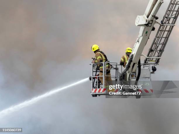 firefighters using hoses on a fire - fireman uk stock pictures, royalty-free photos & images