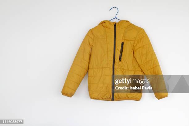 yellow jacket hanging on wall - jacke stock-fotos und bilder