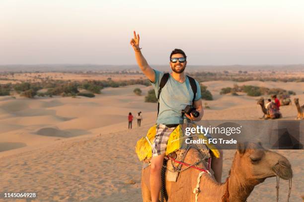 turista a cavallo cammello nel deserto - riding foto e immagini stock