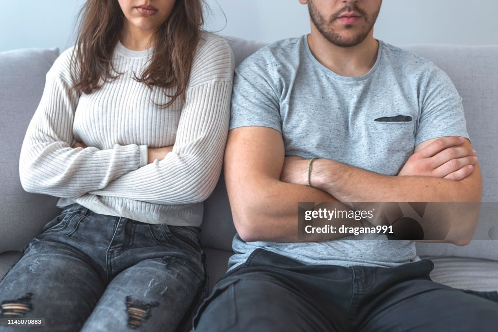 Close up of a couple arguing with the arms crossed.