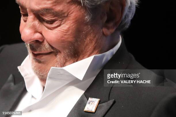French actor Alain Delon, wearing a pin with the December 5, 1991 cover of French weekly Paris Match, reacts after receiving a Honorary Palme d'Or...