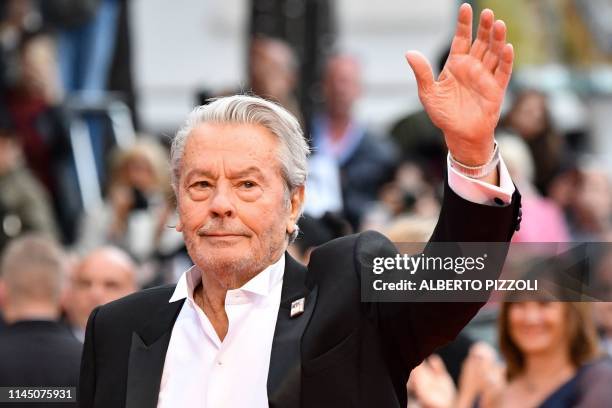 French actor Alain Delon, wearing a pin with the December 5, 1991 cover of French weekly Paris Match, waves as he arrives to be awarded a Honorary...