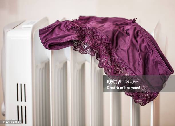 lingerie drying on electric heater convector at home. - bragas fotografías e imágenes de stock