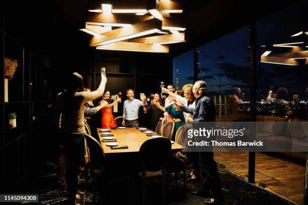 Smiling group of friends toasting before dining in private dining room in restaurant
