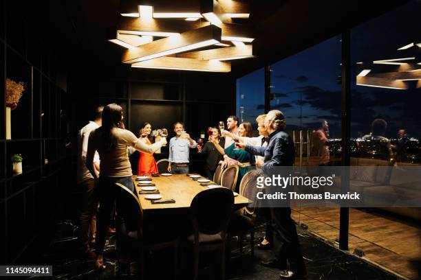 smiling group of friends toasting before dinner in private dining room - exclusive event stock pictures, royalty-free photos & images