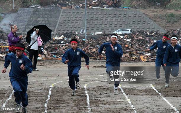 Otomo Junior High School students compete during the athletic meets held at debris-cleared Otomo Elementary School on May 22, 2011 in Rikuzentakata,...