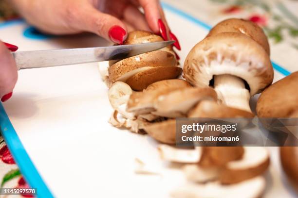woman's hands cutting fresh organic brown mushroom - crimini mushroom stock pictures, royalty-free photos & images