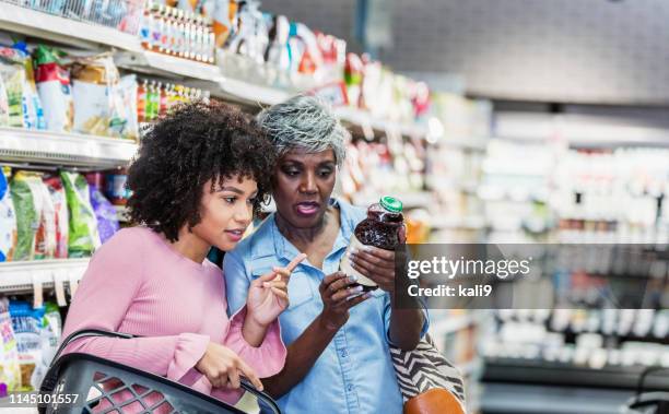 two african-american women in supermarket - nutrition label stock pictures, royalty-free photos & images