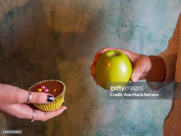 two persons with an apple and a muffin in their hands - austauschen stock-fotos und bilder