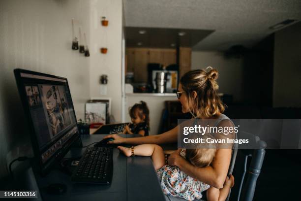 working mother multitasking on the computer and holding baby - busy mom stock-fotos und bilder