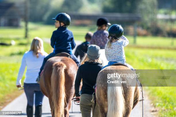 bambini che cavalcano in un parco - andare a cavallo foto e immagini stock