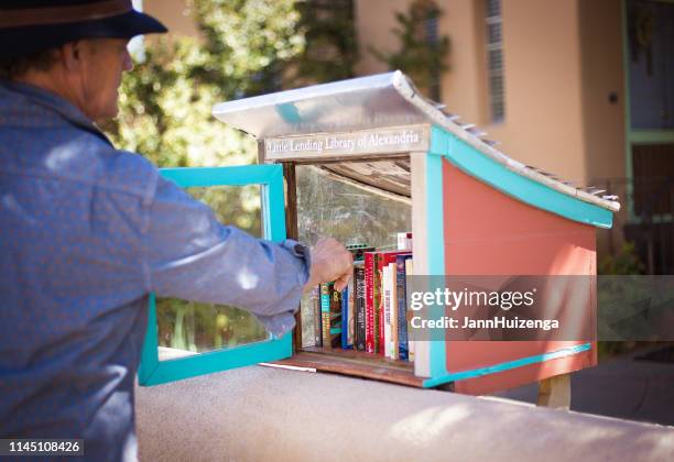 santa fe, nm: man using little free library box - exchanging books stock pictures, royalty-free photos & images