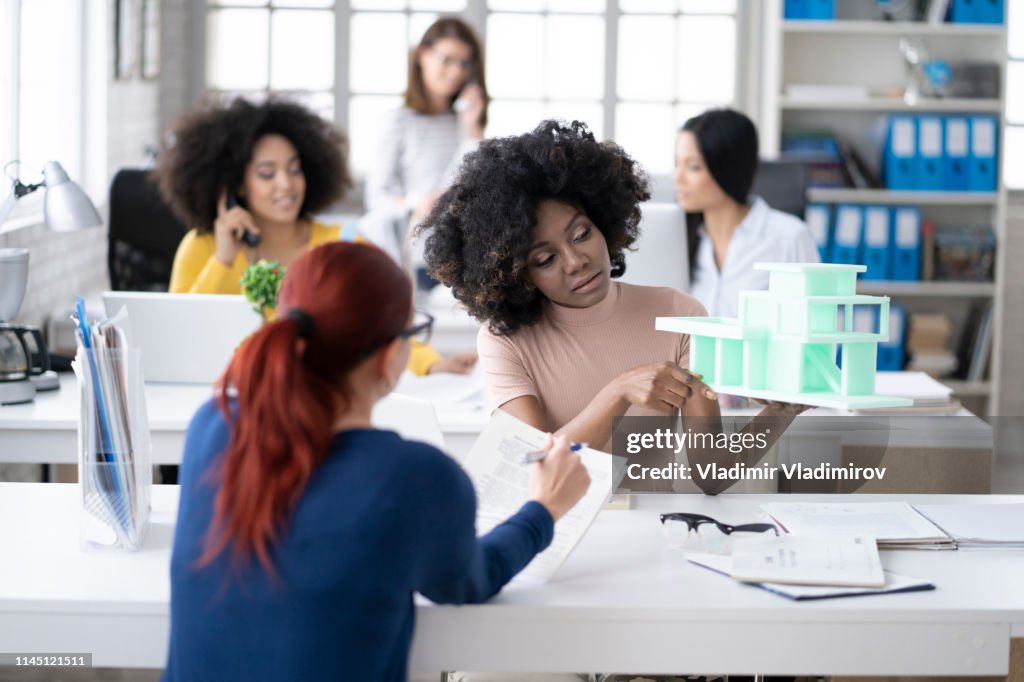 Mulher africana que apresenta o modelo 3D no escritório moderno