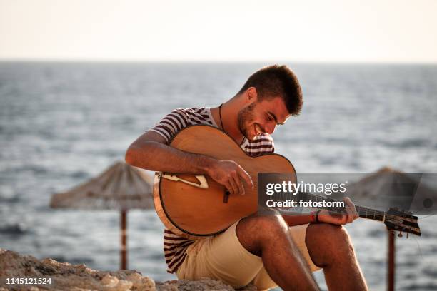 man spelar gitarr på stranden på en solig dag - guitarist bildbanksfoton och bilder