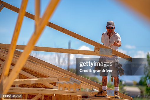 Rugged Carpenter On A Framing Crew Setting Trusses On A New Home High ...