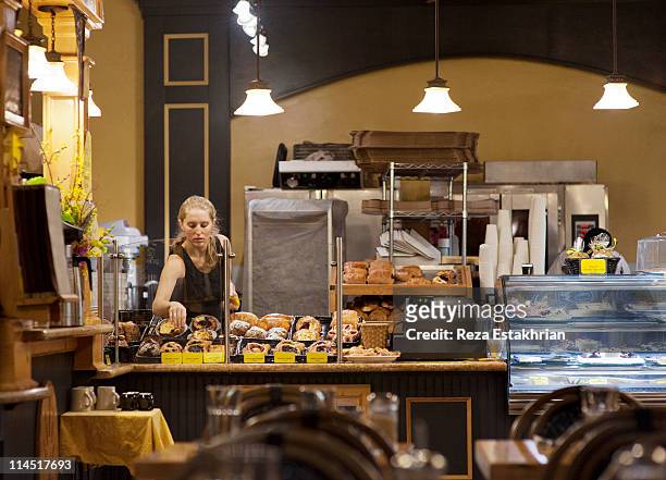 woman presents pastries in showcase - america patisserie fotografías e imágenes de stock