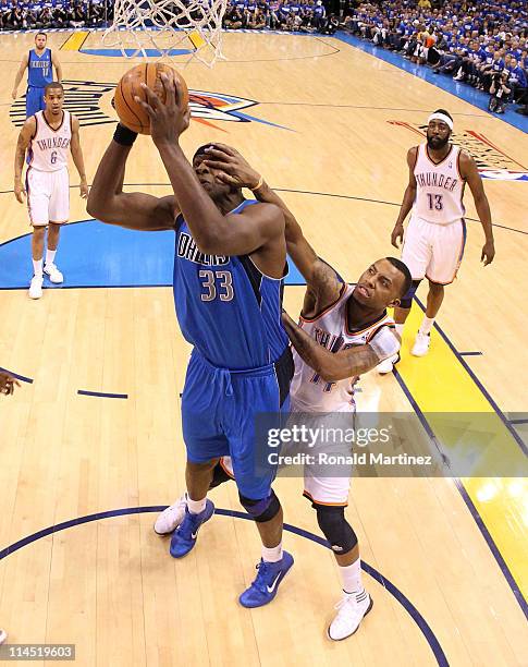 Brendan Haywood of the Dallas Mavericks goes up for a shot as Daequan Cook of the Oklahoma City Thunder grabs his face in Game Three of the Western...