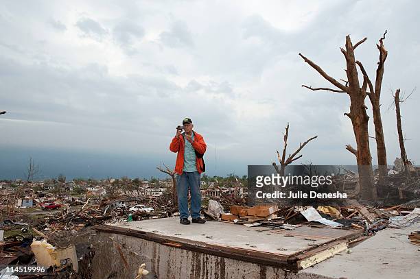 Jim Martin videotapes the damage as he and his wife attempt to salvage medication from her brother's home before a second storm moves in, on May 23,...