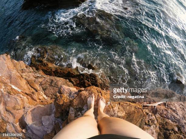 high angle view on the legs of young woman standing on the sea cliff - wearable kamera stock-fotos und bilder