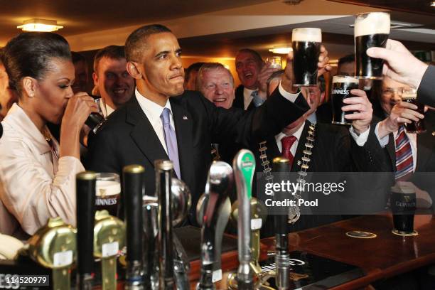 President Barack Obama and First Lady Michelle Obama enjoy a glass of Guinness in his ancestral home of Moneygall, on May 23, 2001 in Moneygall,...