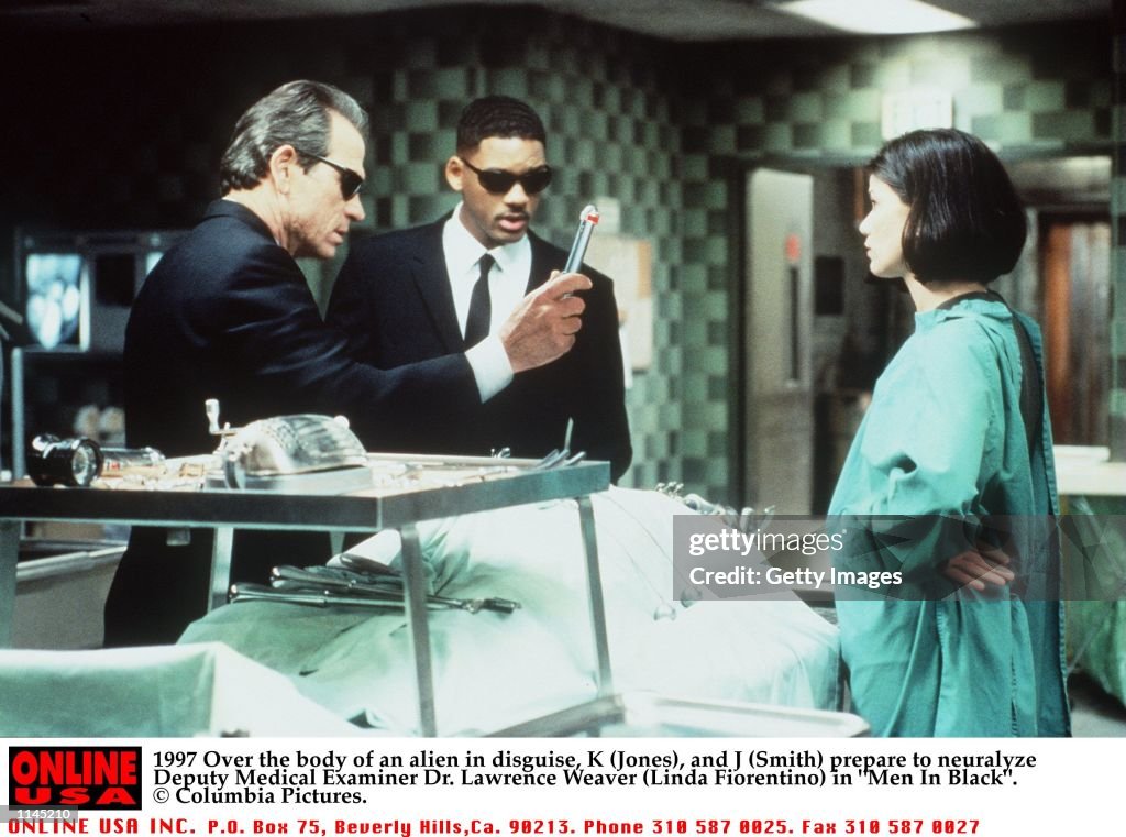 1997 Over the body of an alien in disguise, K (Jones), and J (Smith) prepare to neuralyze Deputy Med