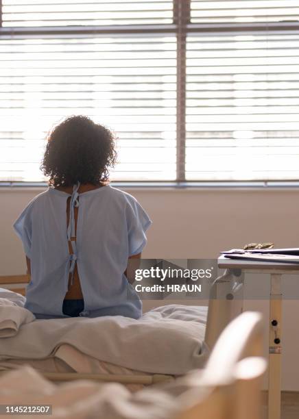 lonely female patient sitting on hospital bed - hospital bed stock pictures, royalty-free photos & images