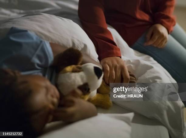 moeder holding ziek zoon de hand slapen op bed - child hospital bed stockfoto's en -beelden