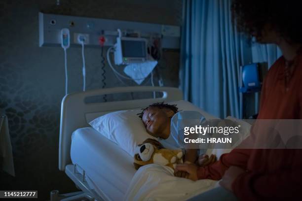 mutter hält kranke knabenschlaf auf bett - boy sitting on bed stock-fotos und bilder