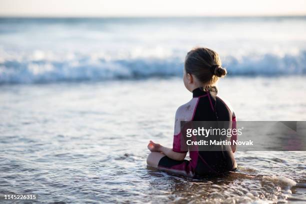 kid practicing meditation at beachfront - vista posterior stock pictures, royalty-free photos & images