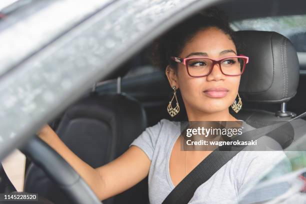 portrait of young woman driving a car - driver license stock pictures, royalty-free photos & images