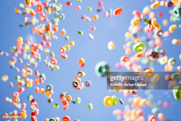 colorful fruit loops cereals levitating in the sky in a beautiful visual effect. - cereal plant stock-fotos und bilder