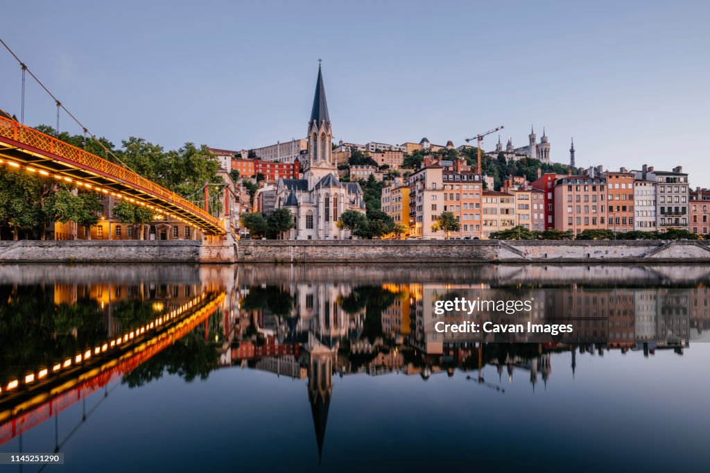 Paul-Couturier Footbridge over Saone river against buildings in city during sunset