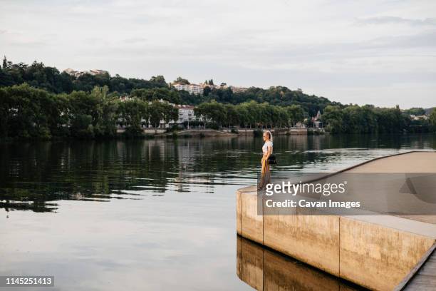 side view of woman looking at saone river while standing against cloudy sky during sunset in city - rhone stock pictures, royalty-free photos & images