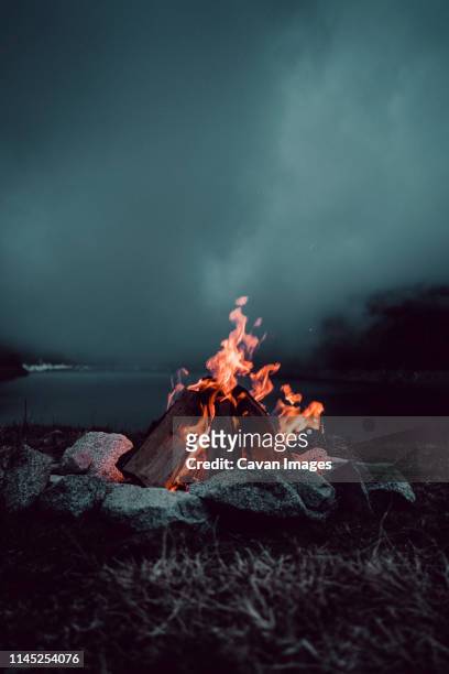 campfire burning on field against cloudy sky during dusk - campfire no people stock pictures, royalty-free photos & images