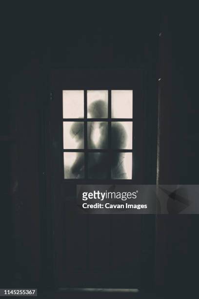 newlywed couple kissing seen through cottage window - coppia passione foto e immagini stock