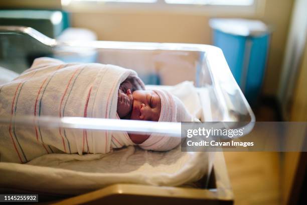 high angle view of cute newborn baby boy sleeping in hospital bassinet - wrapped in a blanket stockfoto's en -beelden