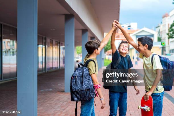 happy friends with arms raised standing on footpath against buildings - signaling pathways stock-fotos und bilder