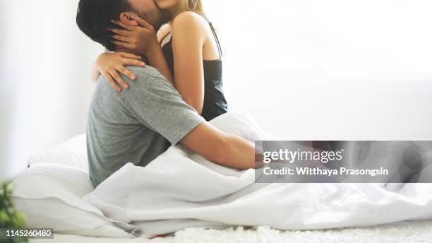 passionate couple is having sex on bed - man and woman kissing in bed stock pictures, royalty-free photos & images