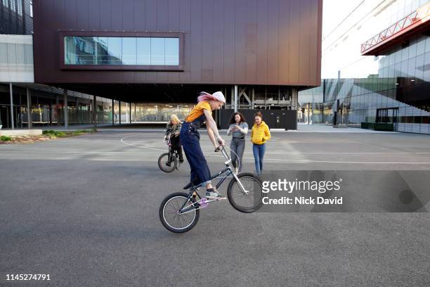 action shot of young woman on bmx doing wheelie - wheelie stock-fotos und bilder