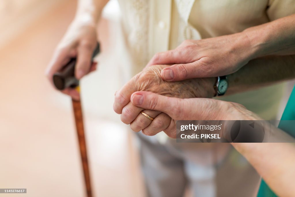 Nurse consoling her elderly patient by holding her hands