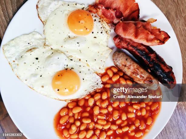 directly above close-up view of traditional english breakfast with fried eggs, beans, sausage and bacon - pork sausage stock pictures, royalty-free photos & images