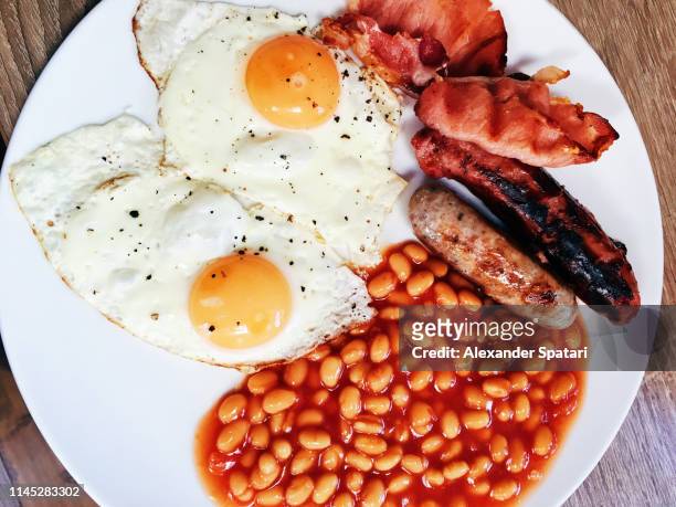 directly above close-up view of traditional english breakfast with fried eggs, beans, sausage and bacon - engelsk frukost bildbanksfoton och bilder
