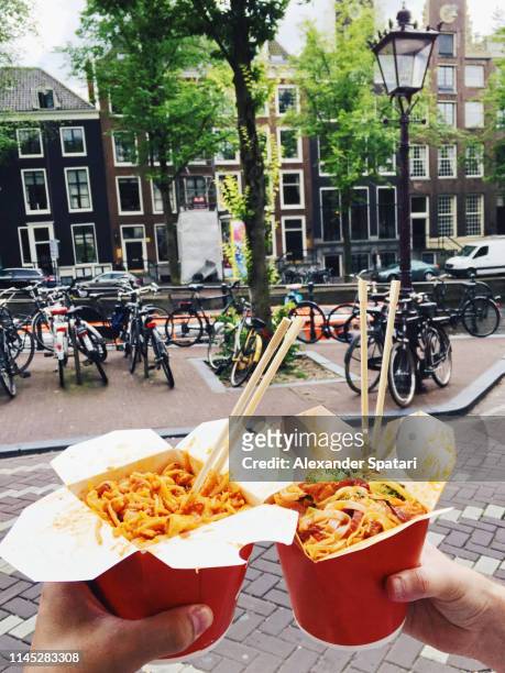 eating chinese takeaway food on the street in amsterdam, personal perspective view - chinese takeout 個照片及圖片檔